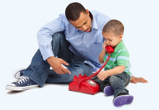 Father sitting with son who is playing with a phone