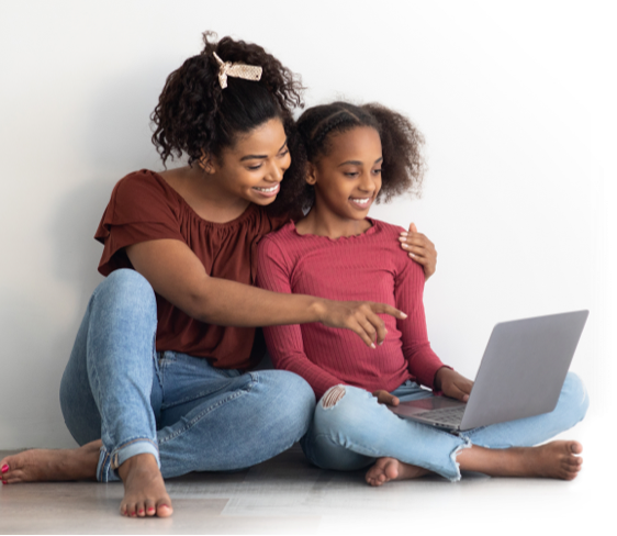 Mother and daughter sitting on the floor looking at a laptop